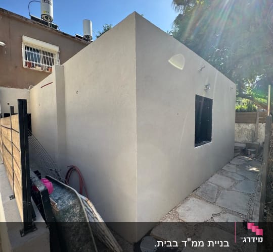 קיר חיצוני עם שביל מרוצף ואביזרי בנייה בצד